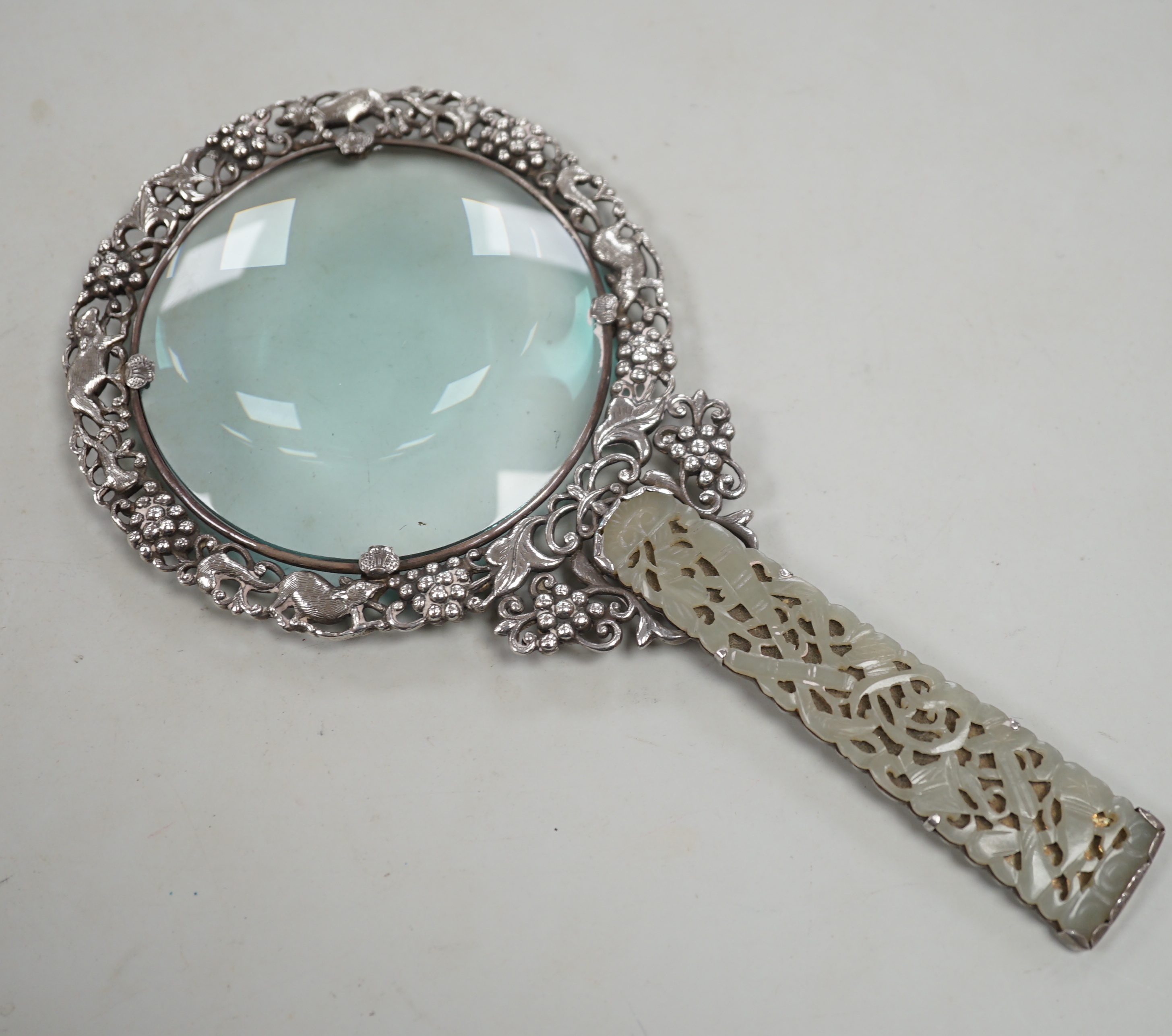 A Chinese white metal and pale celadon jade handled magnifying glass, early 20th century, stamped ‘SILVER’, 19cm long